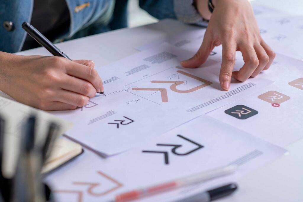 Designer sketching logo concepts on paper with pen